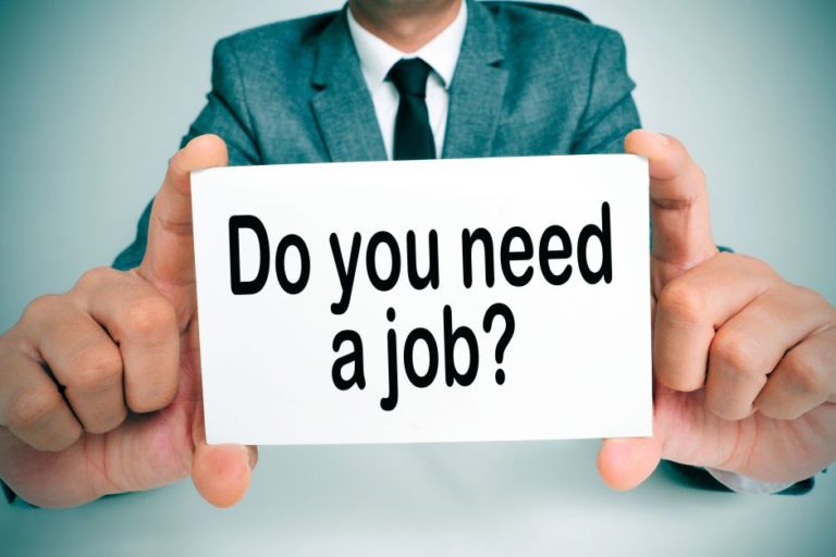 a man wearing a suit holding a signboard with the question do you need a job written on it